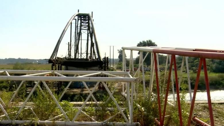 Podul de peste râu care stă pe mal. Mașinile trec Someșul cu bacul