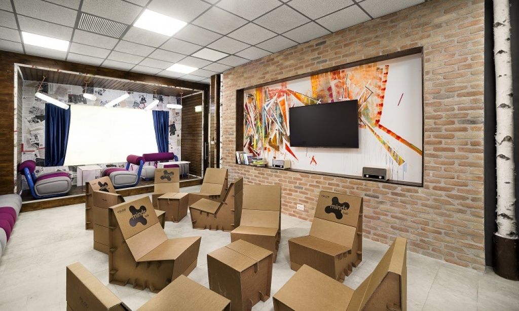 Living-room-ul sau sala unde se tin evenimente si workshop-uri este accesorizata cu scaune din carton.